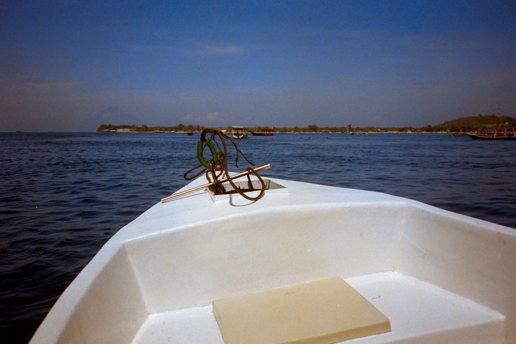 Boat bow navigating ocean toward shoreline