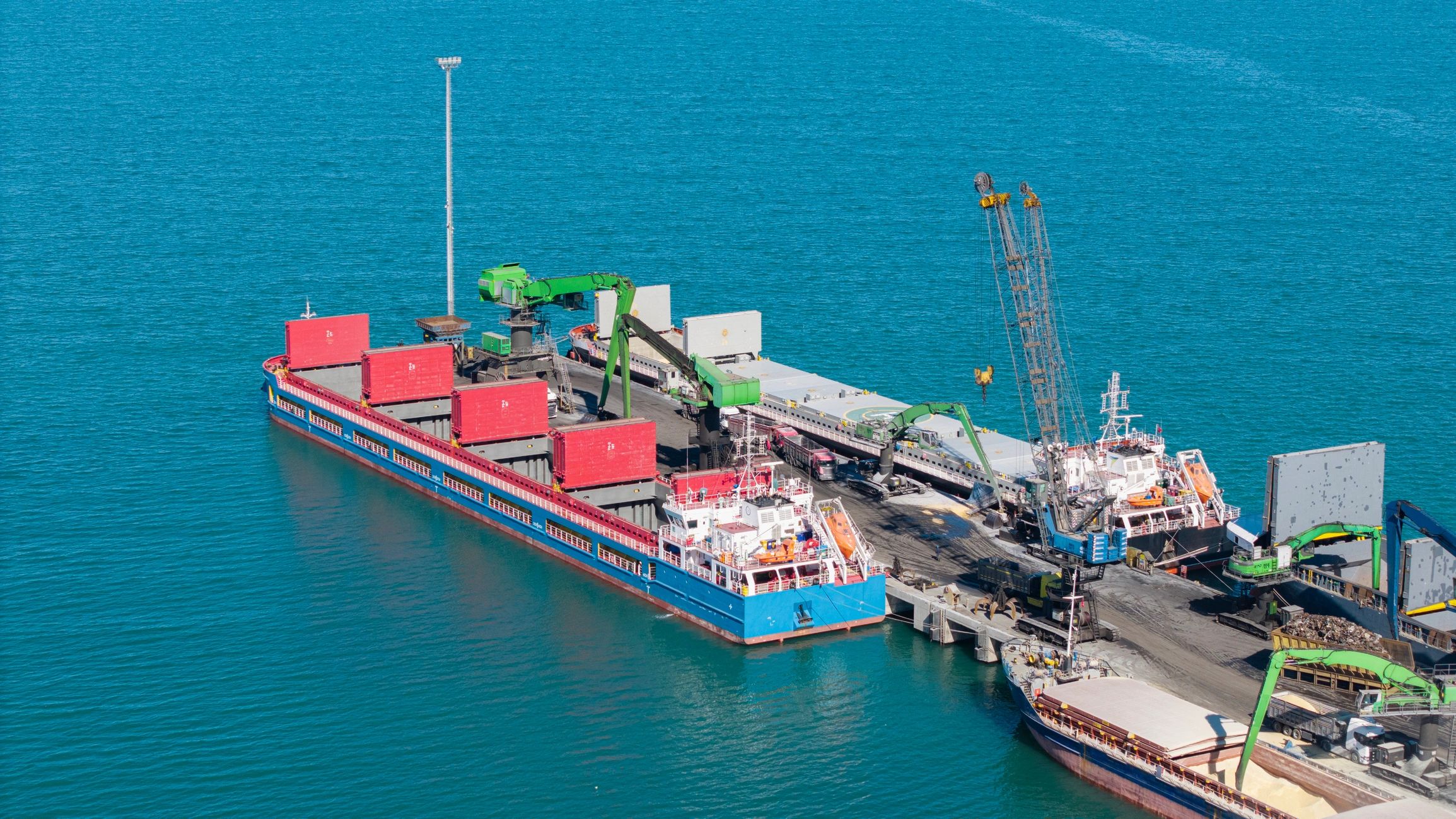 Cargo ship loading bulk freight at busy port terminal